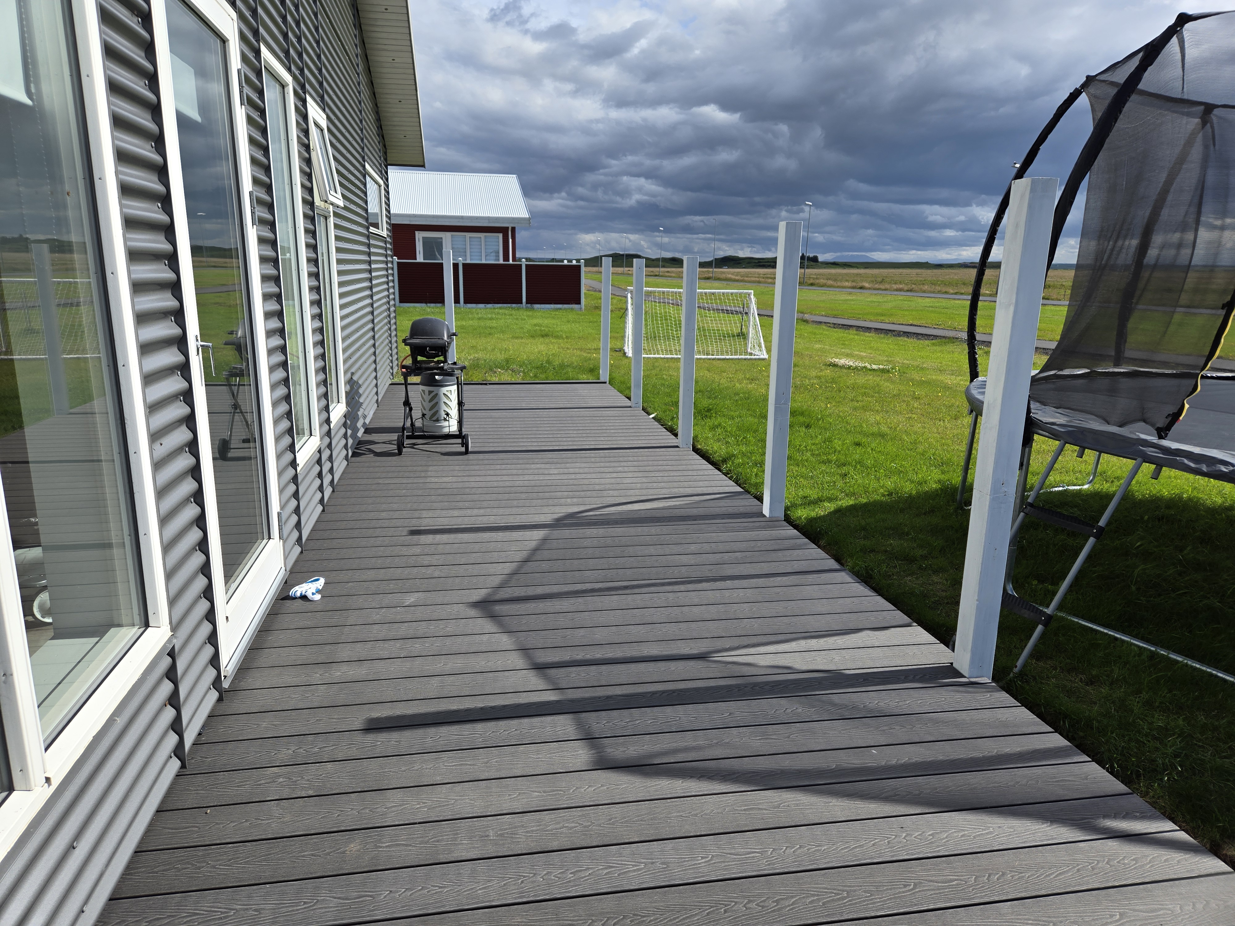 Grátt WPC pallaefni meðfram sumarhúsi á landsbyggðinni